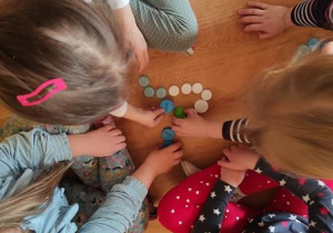 Dzieci układaja z nakrętek kształty liter.